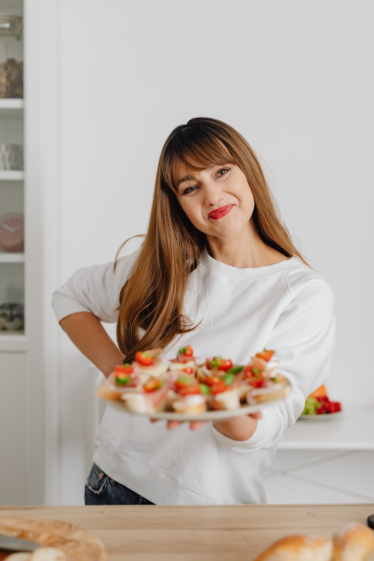 Mujer sonriendo mostrando un plato de comida deliciosa en las manos